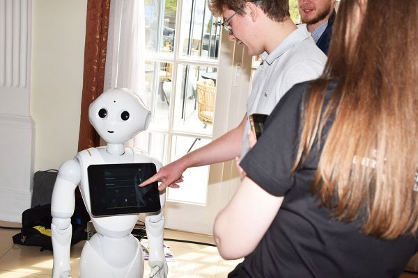 Mężczyzna wskazujący palcem na prezentowanego robota