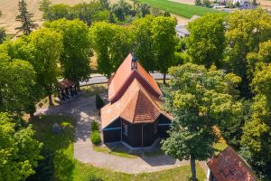 Widok z lotu ptaka na stary kościół, stojący wśród drzew.