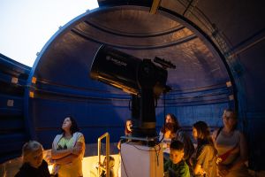 Dzieci i osoby dorosłe pod kopułą obserwatorium astronomicznego.