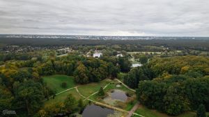 Widok z lotu ptaka na las, stawy, w oddali miasto.