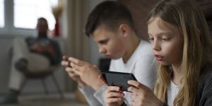 Dziewczynka i chłopiec trzymają w rękach smartfony.