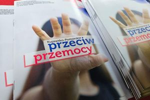 Ulotki z otwartą dłonią oraz napis: Kujawsko-Pomorskie przeciw przemocy.