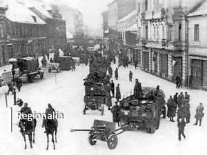 Powojenne, niewyraźne zdjęcie, na którym są kamienice i przemieszczający się ludzie.