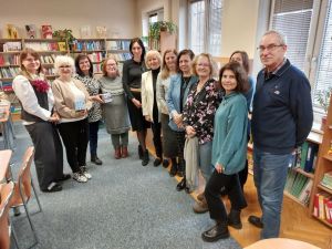 Grupa osób pozuje do zdjęcia w bibliotece.