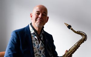 Mężczyzna w średnim wieku z saksofonem w rękach.