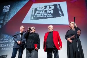 Na scenie festiwalu filmowego dwie kobiety w czarnych strojach oraz dwóch mężczyzn w marynarkach.