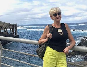 Kobieta w okularach przeciwsłonecznych nad pozuje nad brzegiem morza.