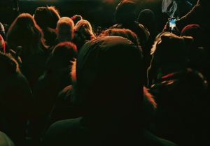 Widziany od tyłu tłum ludzi na koncercie ubranych w kurtki i czapki.