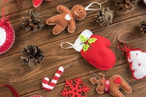 Kolorowe filcowe ozdoby świąteczne: renifer, piernik, choinka, gwiazdka, między nimi szyszki.