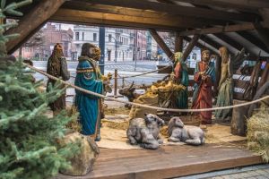 Uliczna szopka świąteczna z drewnianymi figurami ludzi i zwierząt.