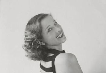 Uśmiechnięta piękna i młoda kobieta o falowanych włosach do ramion pozuje do zdjęcia.