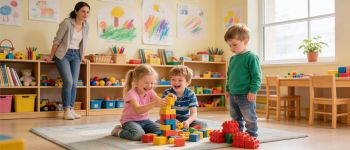Dwoje uśmiechniętych dzieci i jedno smutne w przedszkolu. Nauczycielka obserwuje zachowania dzieci.