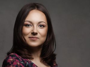 Twarz ciemnowłosej uśmiechniętej kobiety.