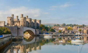 Zamek i most oraz płynące żaglówki.