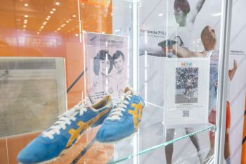 Fragment wystawy: obuwie sportowe i zdjęcia sportowców.