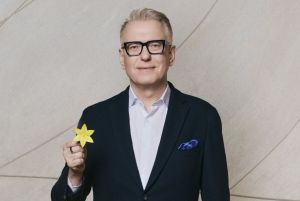 Mariusz Szczygieł z papierowym żonkilem w dłoni.