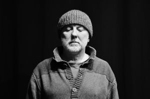 Mężczyzna w czapce, patrzący w dół na czarno-białym zdjęciu.