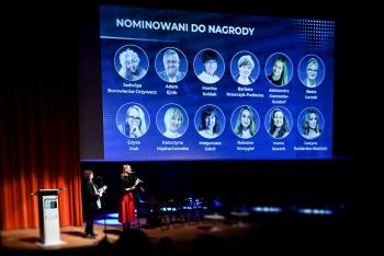 Dwie kobiety na scenie przy mikrofonach. Nad nimi duży ekran z wizerunkami i nazwiskami nominowanych do nagrody.