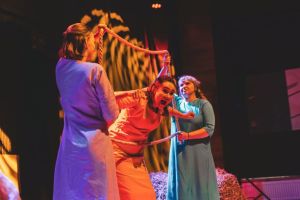 Trzy kobiety podczas spektaklu teatralnego.