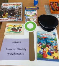 Książki o pociągach, czapka kolejarska, kredki, napis: peron pierwszy.
