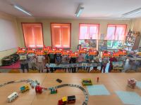 Dzieci stoją w rzędzie i pokazują pokolorowaną lokomotywę oraz książkę.