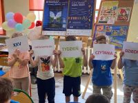 Dzieci pokazują napis: XXV Ogólnopolski Tydzień Czytania Dzieciom.