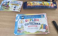 Kolorowe dyplomy i zakładki do książek rozłożone na stoliku.