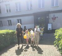 Dzieci z nauczycielkami wychodzą z biblioteki, trzymając w rękach balony i idą do przedszkola.