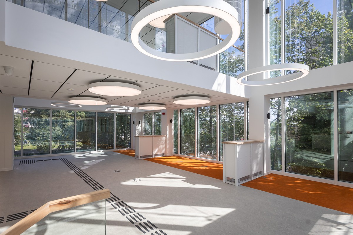 Wnętrze nowoczesnego, przeszklonego pomieszczenia Książnicy z białymi lampami.