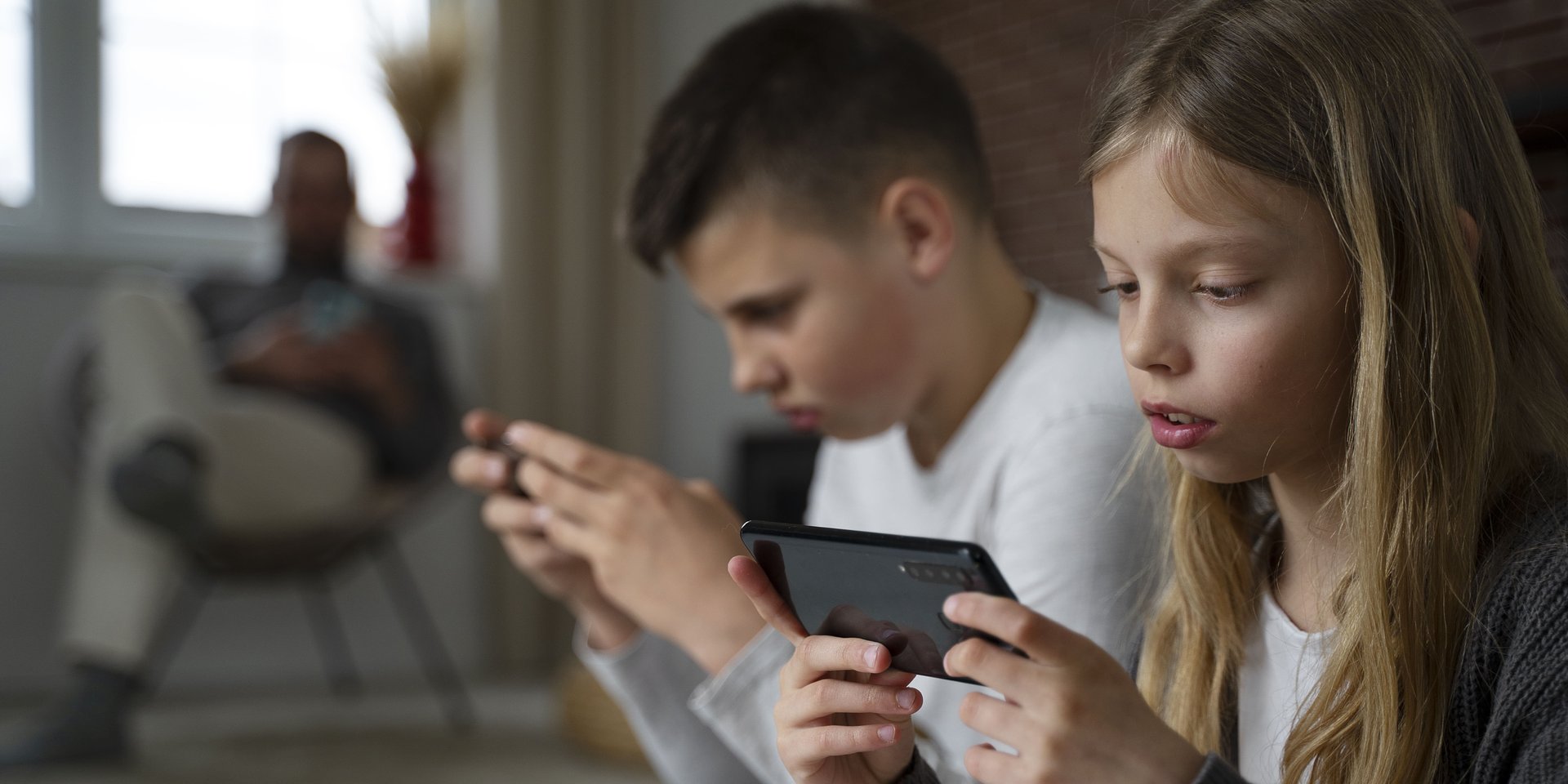 Dziewczynka i chłopiec trzymają w rękach smartfony.