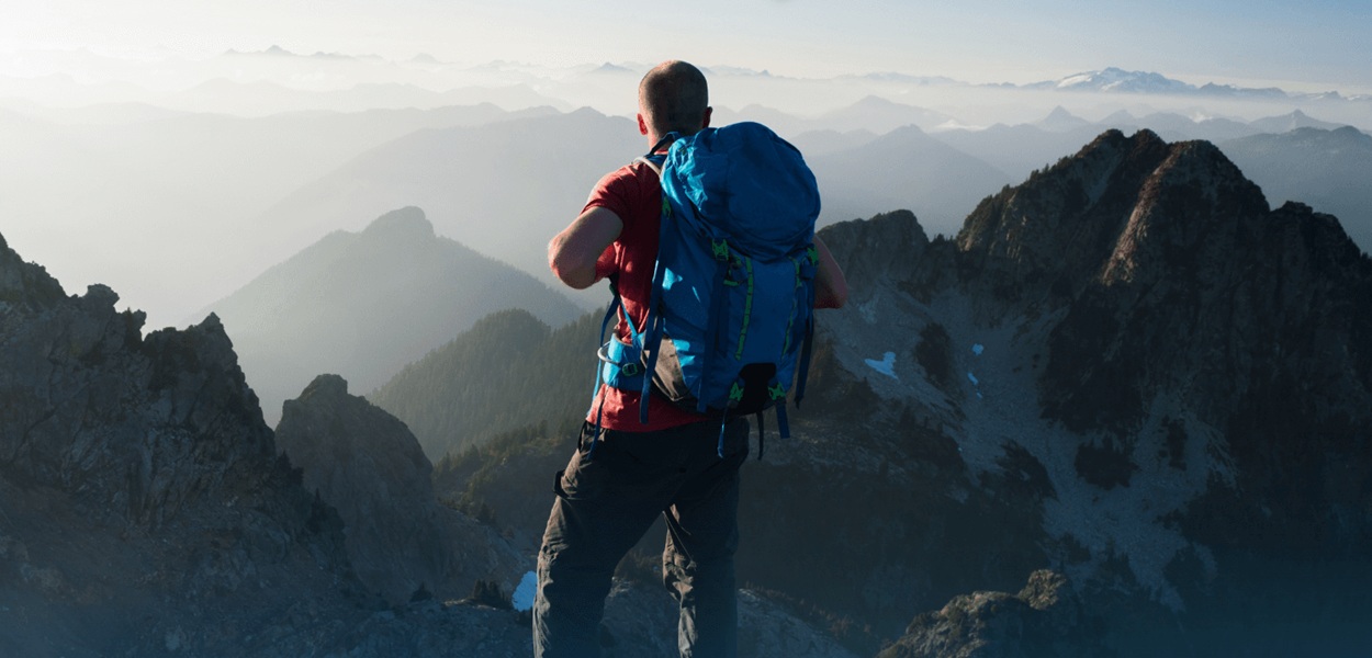 Mężczyzna z plecakiem na szczycie góry.