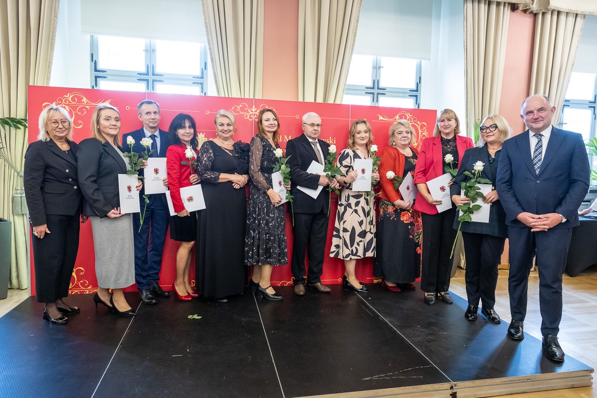 Osoby w oficjalnych strojach pozują z różami i teczkami z herbem woj. kujawsko-pomorskiego.