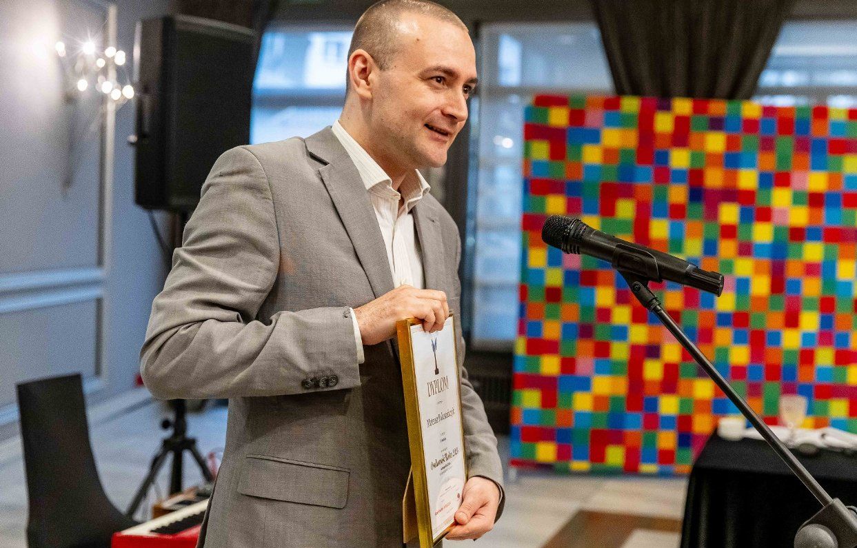 Mężczyzna trzyma w ręku dyplom.