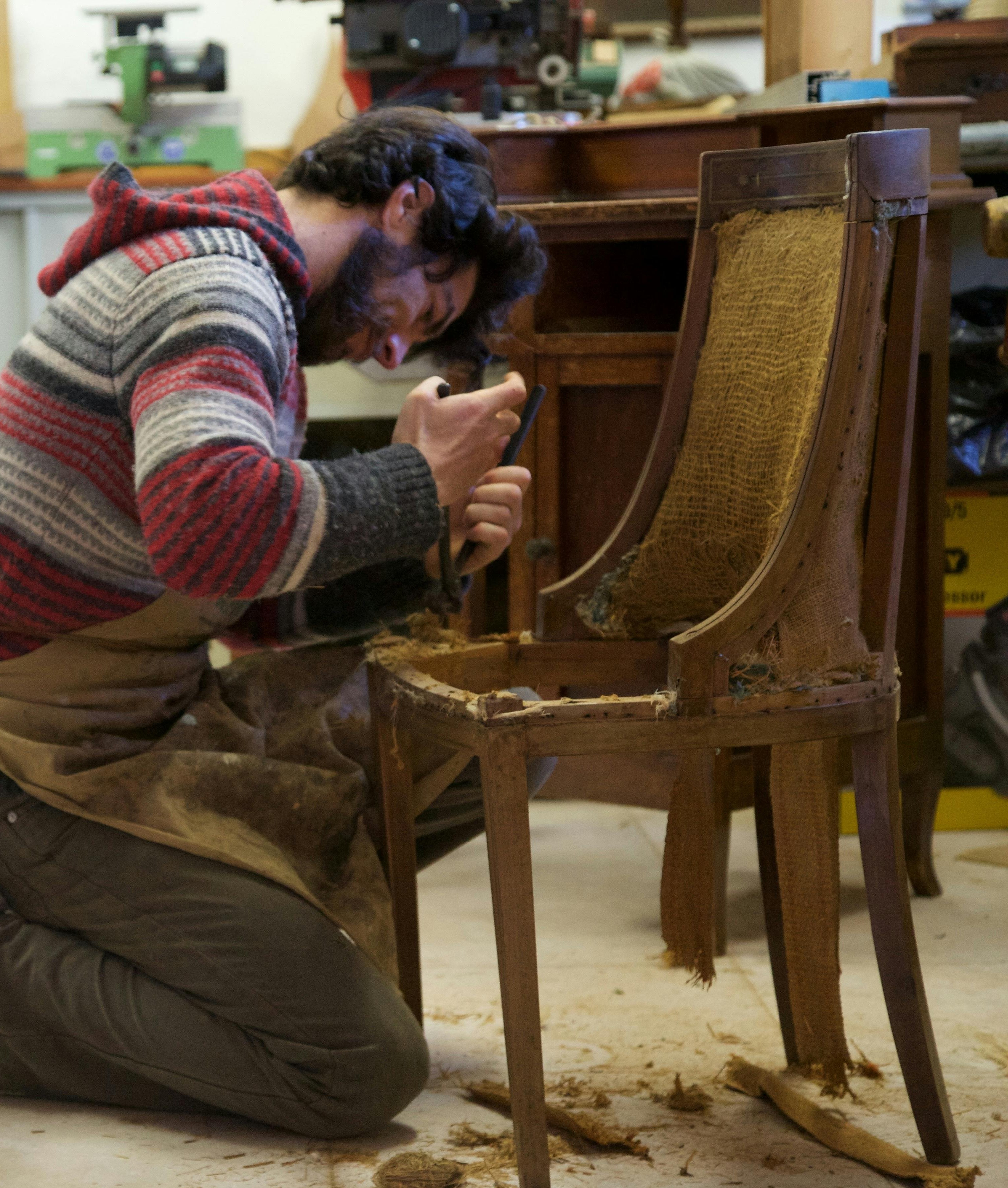 Mężczyzna naprawia stare krzesło.