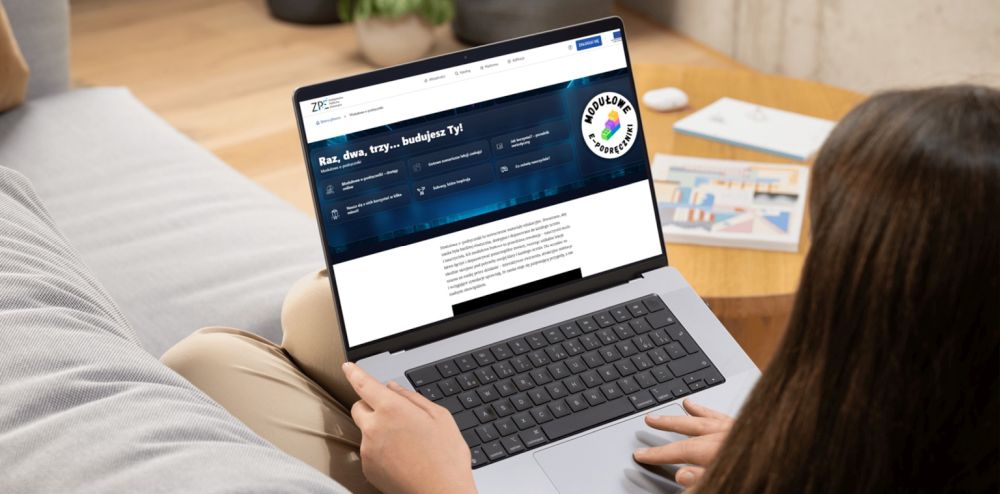 Kobieta siedzi na sofie i trzyma laptopa na kolanach.