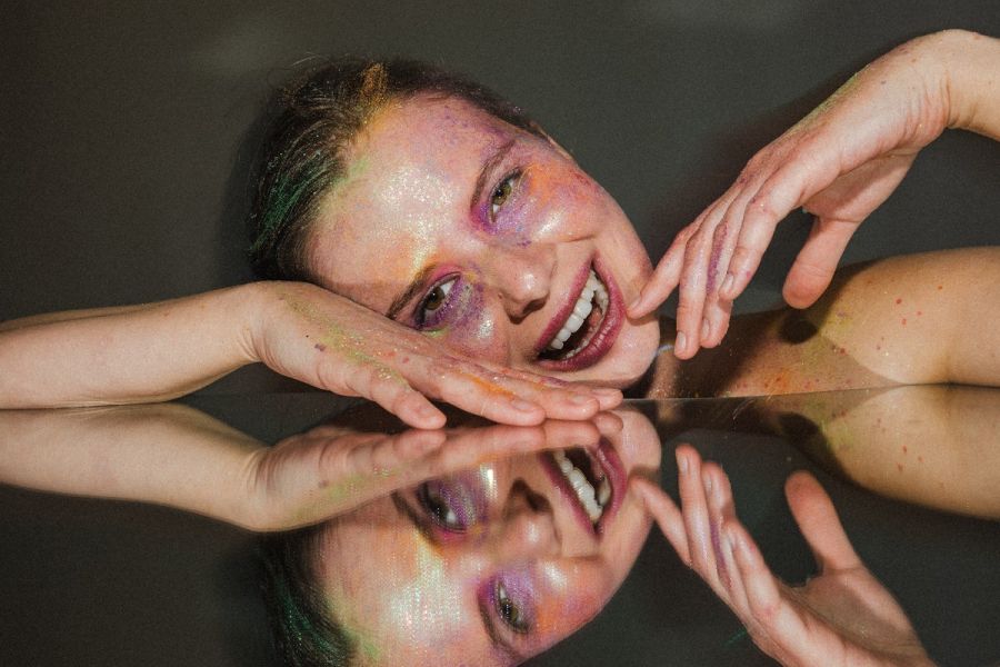 Twarz i dłonie aktorki z mocnym makijażem scenicznym.