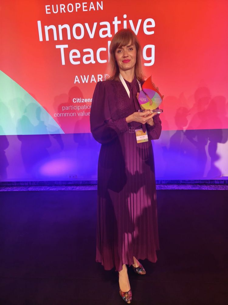 Kobieta trzyma statuetkę na tle banera European Innovative Teaching Award.
