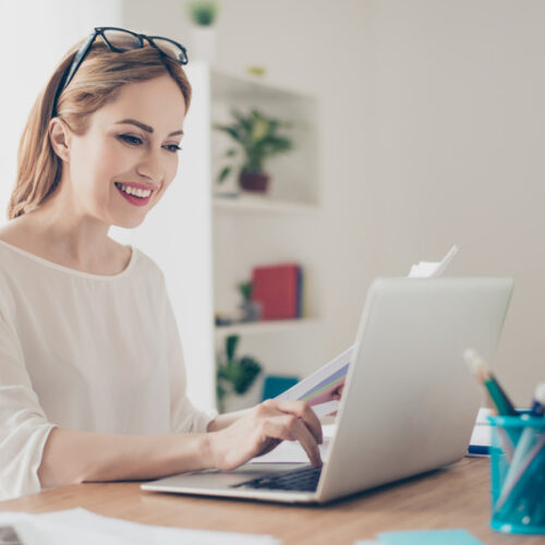 Uśmiechnięta kobieta korzysta z laptopa.