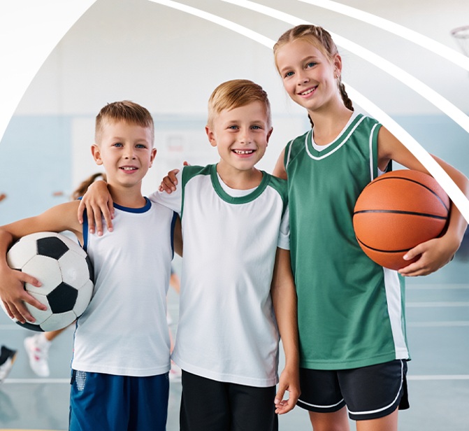 Troje dzieci w strojach sportowych z piłkami.