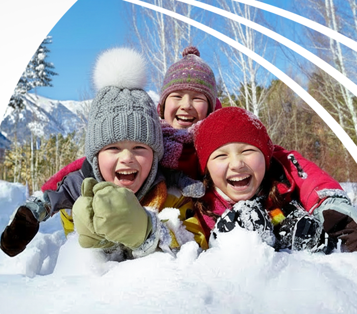 Troje roześmianych dzieci bawi się na śniegu w górach.