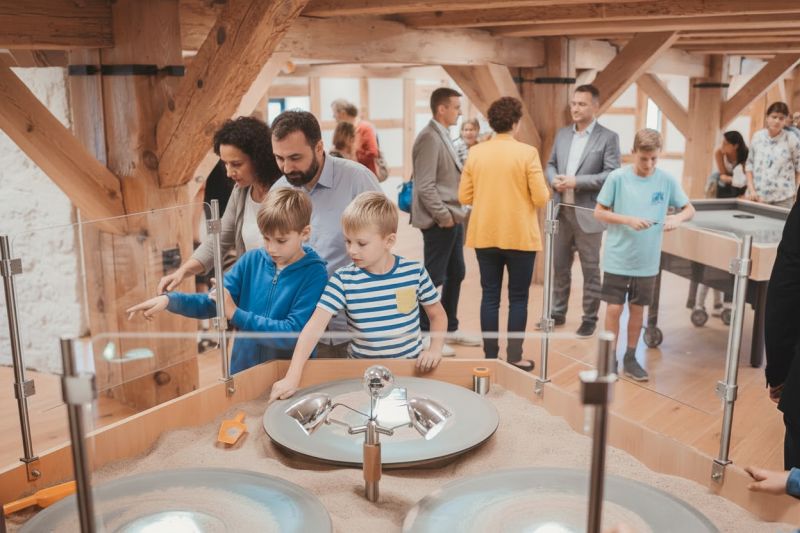 Dzieci i dorośli w sali z eksponatami i urządzeniami do eksperymentów.