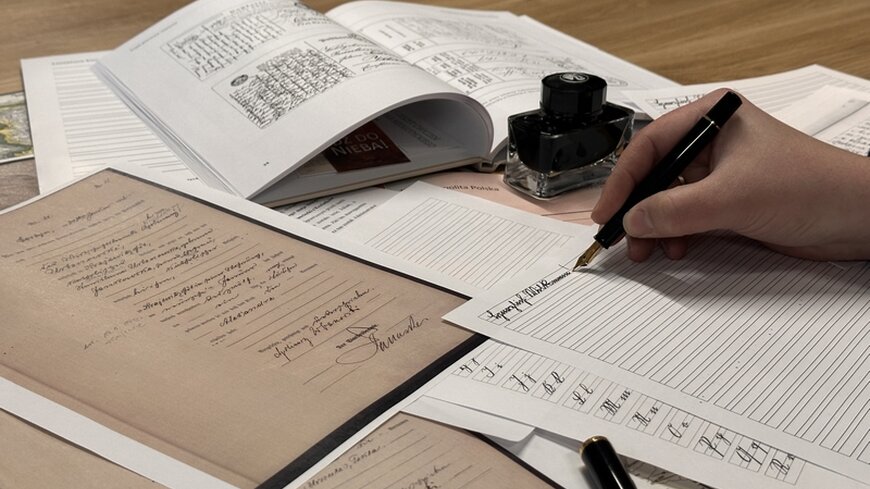 Dokumenty archiwalne, kałamarz, pióro wieczne w dłoni. 