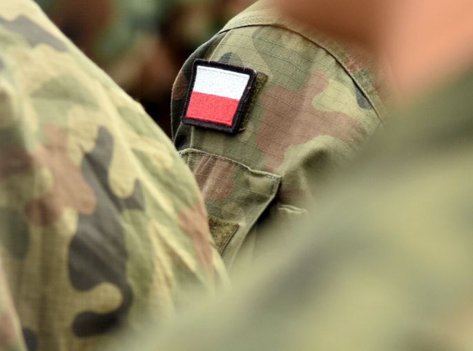 Żołnierze w mundurach polowych z polską flagą na ramieniu