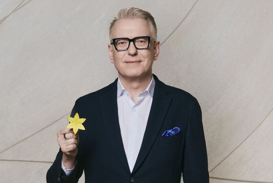 Mariusz Szczygieł z papierowym żonkilem w dłoni.