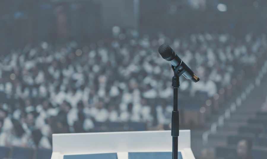 Zbliżenie na mikrofon w dużej sali konferencyjnej.