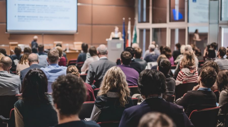 Duża sala konferencyjna z prelegentką i słuchaczami.