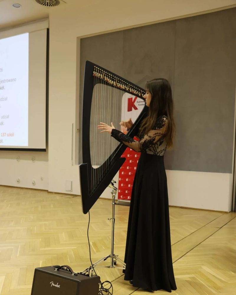 Uczennica gra na harfie elektrycznej.