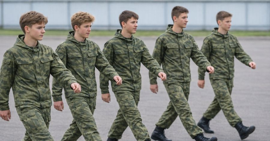 Pięciu chłopaków w mundurach polowych (panterkach) podczas musztry.