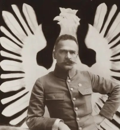 Wizerunek Józefa Piłsudskiego w mundurze na tle wielkiego orła białego.