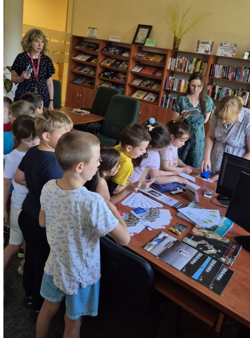 Dzieci stoją w jednym z pomieszczeń biblioteki, które jest kolejnym peronem w zabawie.